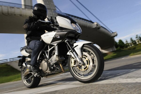 A motorcyclist in a black helmet rides at speed