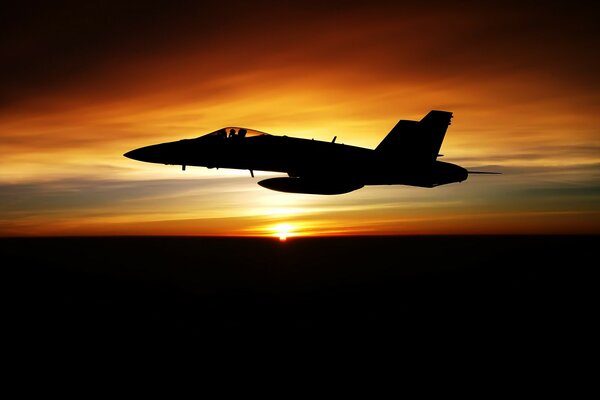 Bei Sonnenuntergang fliegt die Silhouette eines Kampfjets