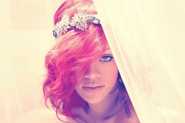 La cantante Rihanna con i capelli rosa con una bella tiara tra i capelli dietro le tende