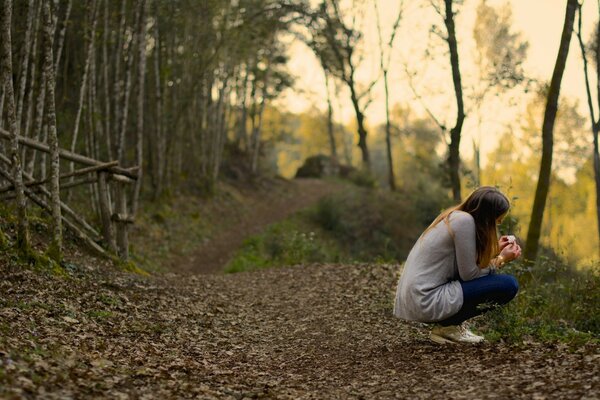 Ragazza seduta nella foresta con le spalle