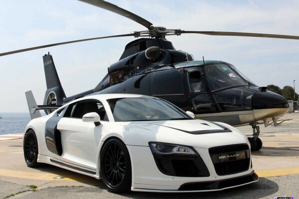 Audi and helicopter stand side by side in bright weather