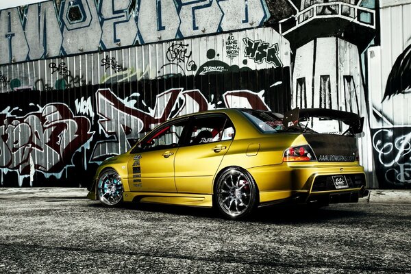 Mitsubishi giallo su sfondo muro con grafite