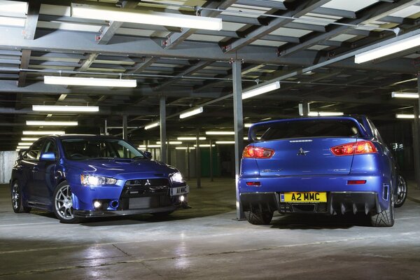 Dos Mitsubishi azules en el estacionamiento cubierto