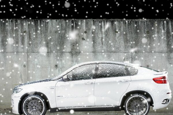 Blanc BMW X6 sous la neige qui tombe