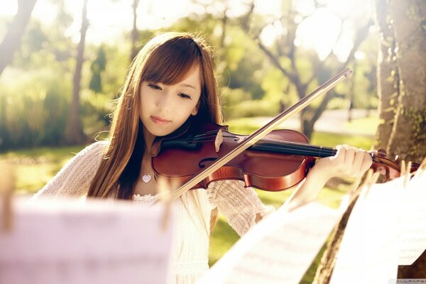 Asiatische Frau spielt Geige nach Noten