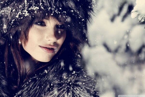 Mujer en invierno en un abrigo de piel en el bosque