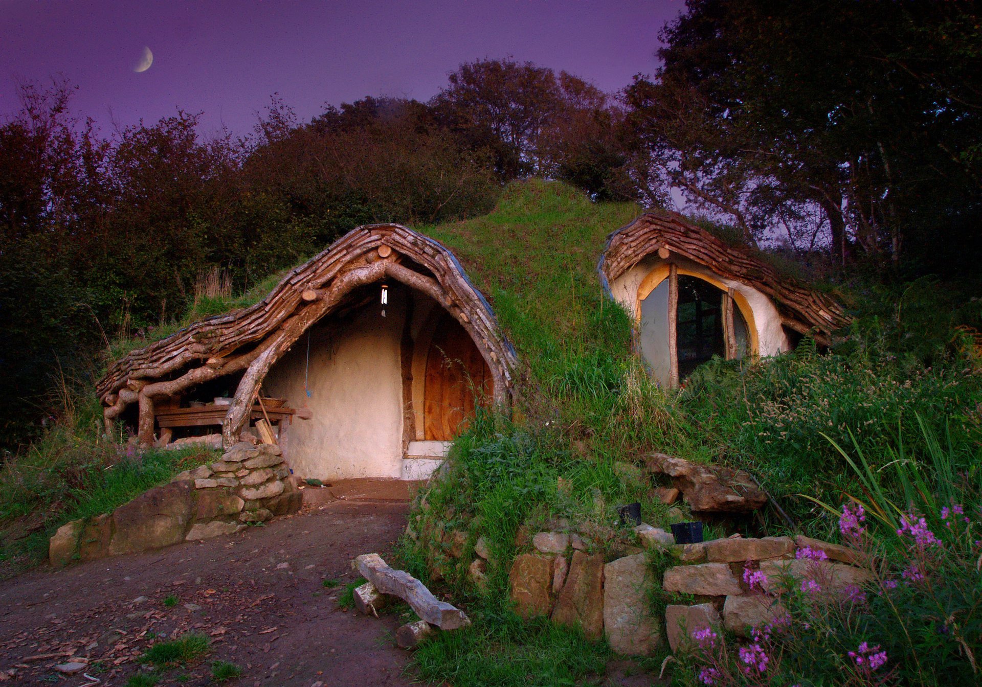 bilbo & frodo bag-end hobbiton ziemianka kwiaty prowizoryczny sklepik lord of the rings the shire john ronald reuel tolkien krajobraz natura lato trawa zieleń kamienie wieczór liliowe niebo księżyc domek drzewa zarośla krzewy dziki kamień