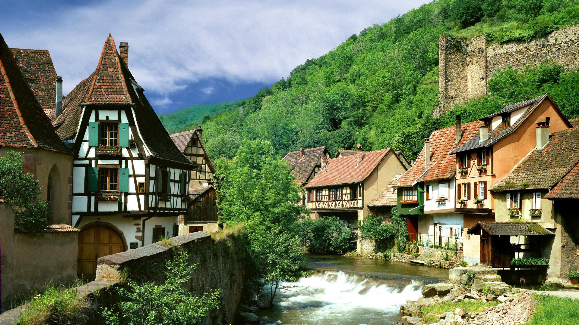 maisons au bord de l eau été paysage montagnes verdure végétation fourrés maisons rivière courant village ciel nuages toits