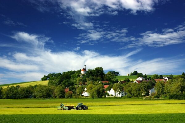 Haymaking on a green meadow near a hill