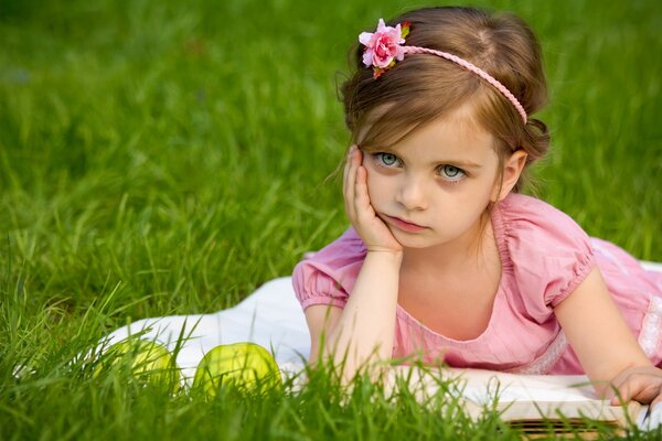 Bambino sul prato inglese con il libro e le mele nella meditazione