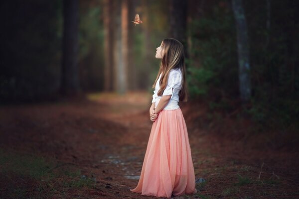 Chica en falda rosa en el bosque con un pájaro