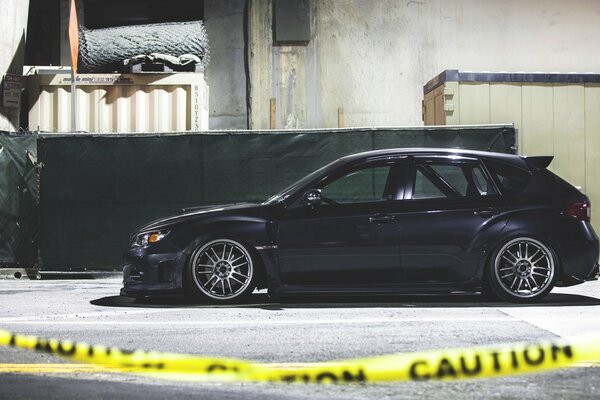 Side view of a black subaru through a yellow ribbon