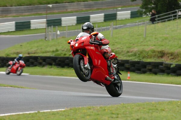 Red motorcycle on the track on the rear wheel