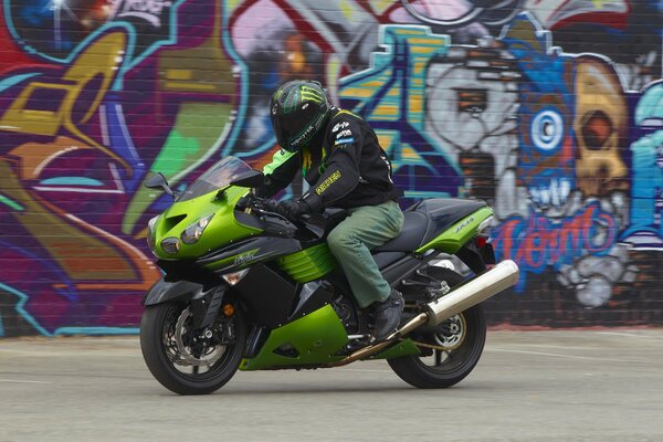 Ein Mann auf einem Motorrad auf einem Graffiti-Hintergrund an der Wand