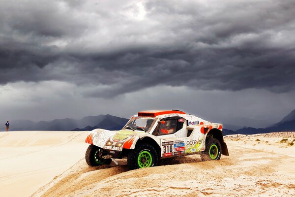 El coche viaja por el desierto bajo las nubes de tormenta