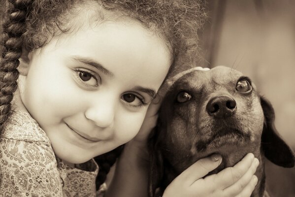 Una bambina accarezza un piccolo cane