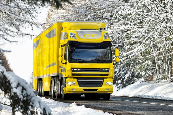 In winter, a yellow truck drives on a snowy road