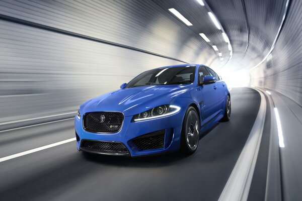 Blue jaguar in a tunnel with big headlights