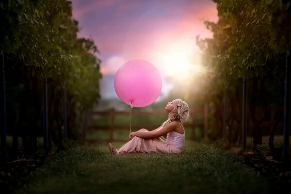 Fille avec une boule rose assise sur l herbe