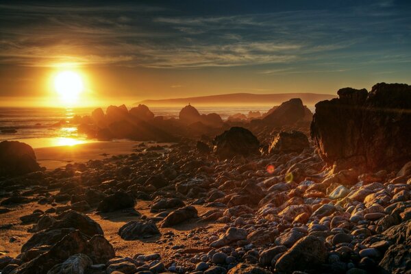 Piedras en la orilla del mar y puesta de sol