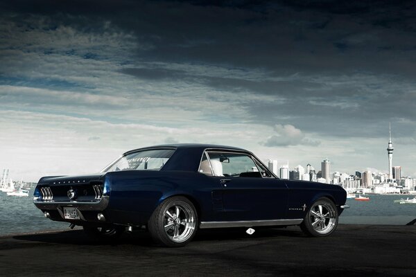 Ford Mustang azul en el fondo de la ciudad vista trasera