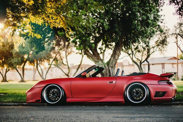 Coche rojo convertible Porsche y árboles verdes