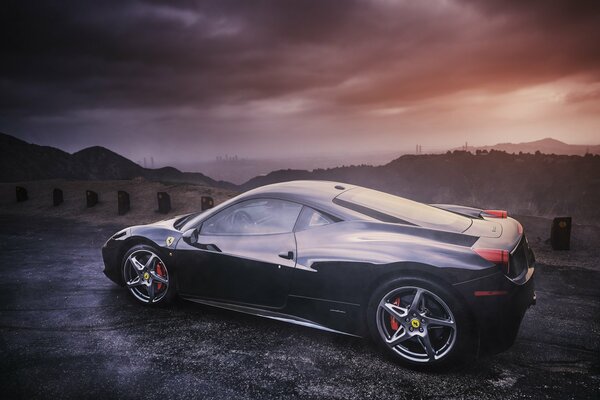 Ferrari nera di profilo sullo sfondo delle montagne