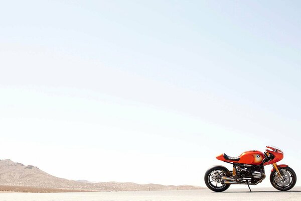 Moto arancione su uno sfondo di cielo e montagne