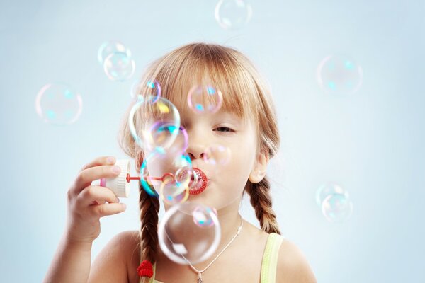 A girl with pigtails blows bubbles