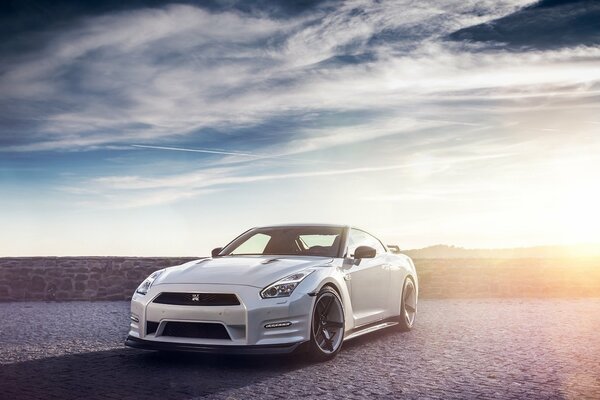 White Nissan on the background of the daytime sky in the light of the sun