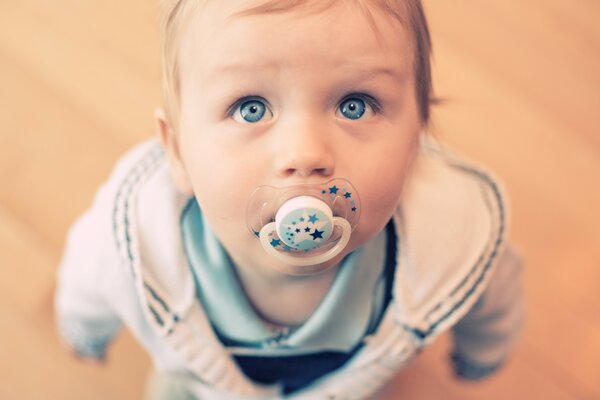 Bébé avec de beaux yeux bleus suce une sucette