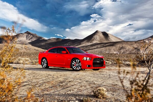 Berlina rossa su uno sfondo di montagne e cielo