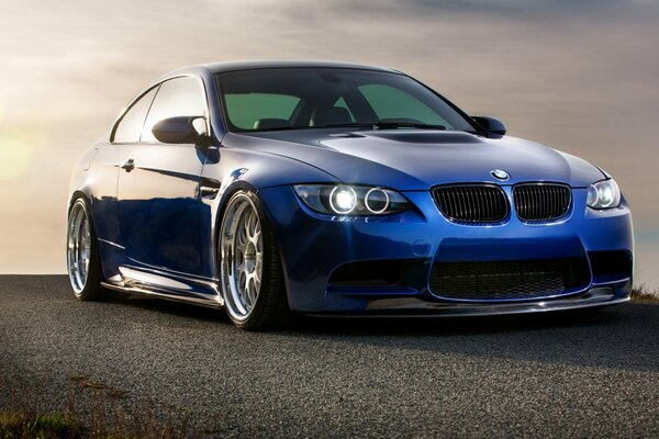 Blue BMW m3 on the background of the setting sun