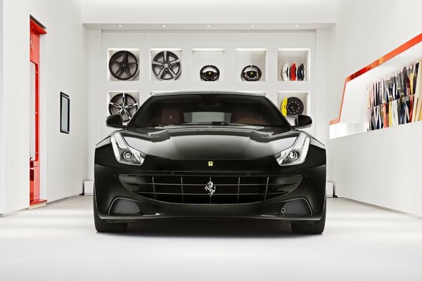 Ferrari nera in garage su sfondo muro con dischi