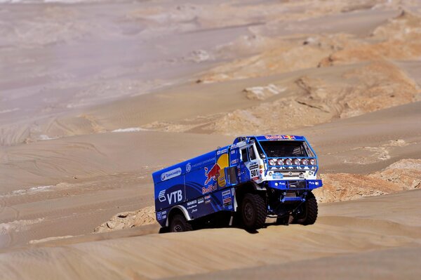 A blue cargo car on a sand background