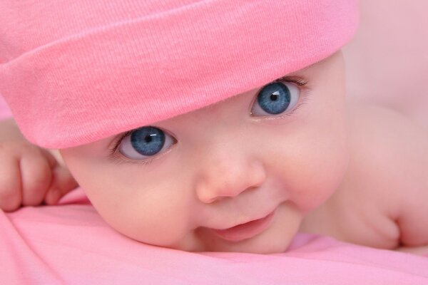 A child with blue eyes in a pink hat