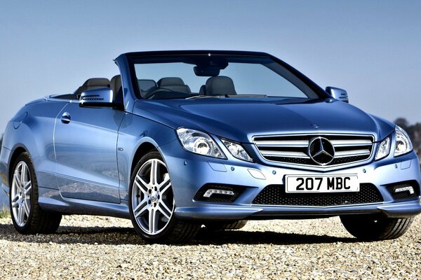 Beautiful blue Mercedes class convertible car by the river on a blue sky background