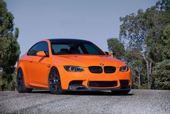BMW naranja detrás de los árboles