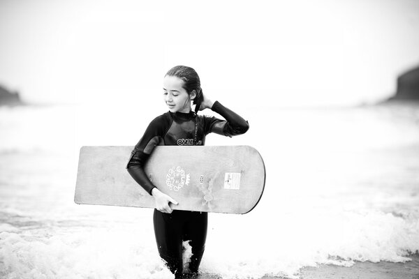 Foto in bianco e nero di una ragazza con surf in mano