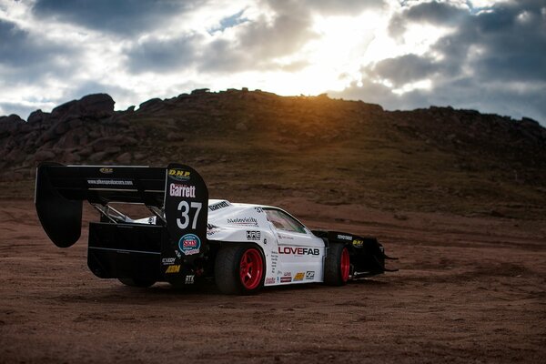 Samochód sportowy jedzie o zachodzie słońca po piasku