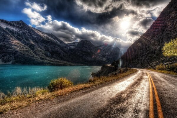 Paved road between mountains and water