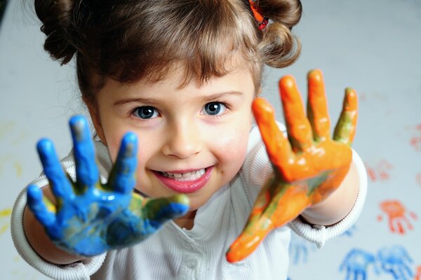 Mädchen in blauer Farbe der rechten Handfläche und orange Farbe der linken Handfläche