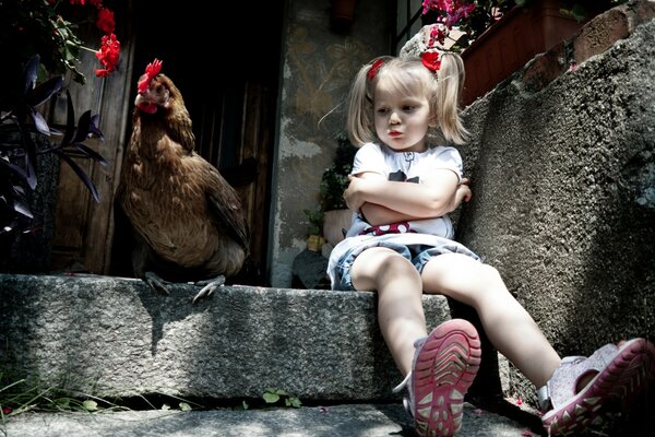 Chica con el pelo blanco se sienta en las escaleras junto a un pollo