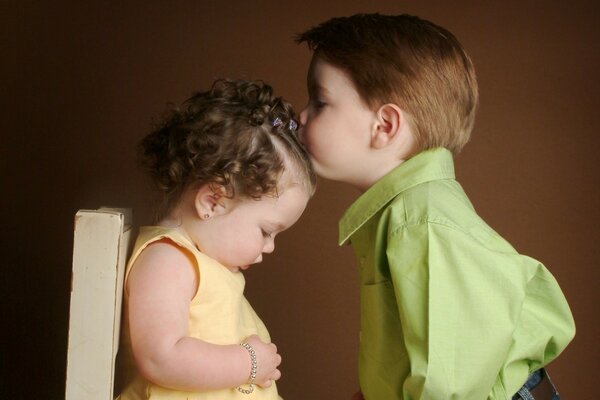 A boy kisses a girl on the head