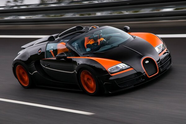 Un coche de carreras negro y naranja conduce sobre el asfalto