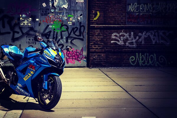 Motocicleta azul estacionada detrás del graffiti