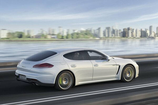 Ein weißer Porsche Panamero fährt auf dem Asphalt vor dem Hintergrund der Stadt