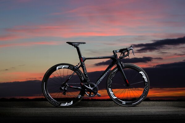 Schwarzes Carbonfahrrad auf Sonnenuntergang Hintergrund