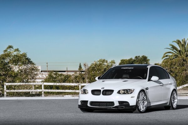White bmw m3 e90 on a background of trees
