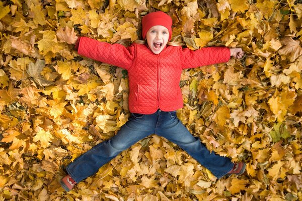 Un niño con una chaqueta roja se baña en las hojas